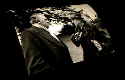 [Photographie originale figurant  Georges Simenon conversant avec un homme].