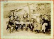 Une photographie originale ancienne en noir et blanc, d'un groupe 10 villageois regroupés autour d'une table de jardin, se restaurant, buvant et ...