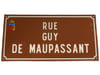 RUE GUY DE MAUPASSANT. Belle plaque de rue &eacute;maill&eacute;e, fond brun et texte blanc en relief. Ville de Ouistreham en Normandie. . MAUPASSANT, Guy de. 