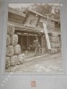 Photographie argentique ancienne représentant un homme avec son vélo face à la devanture d'un magasin de saké, loto et promotion "Kawa Goe Shop". ...