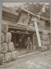 Photographie argentique ancienne représentant un homme avec son vélo face à la devanture d'un magasin de saké, loto et promotion "Kawa Goe Shop". ...