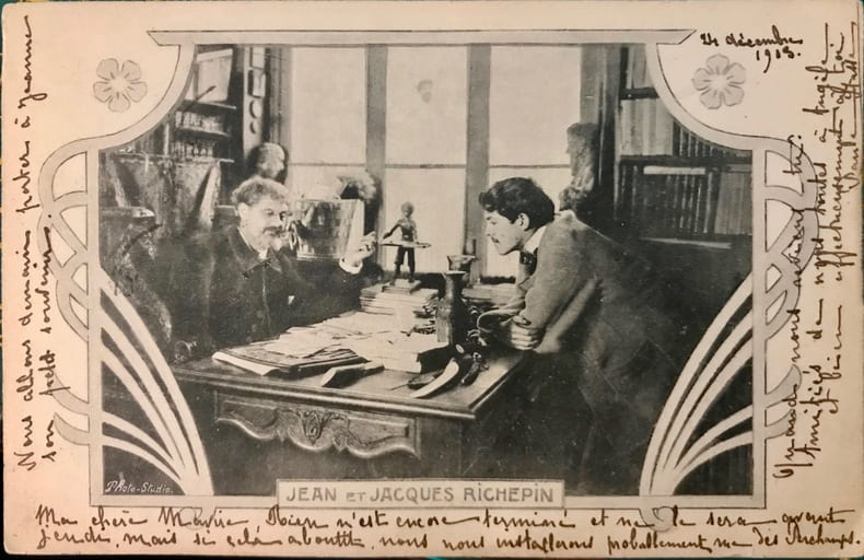Carte postale repr&eacute;sentant le po&egrave;te Jean Richepin et son fils Jacques, po&egrave;te et auteur dramatique, dans leur bureau, dans un encadrement “art ...